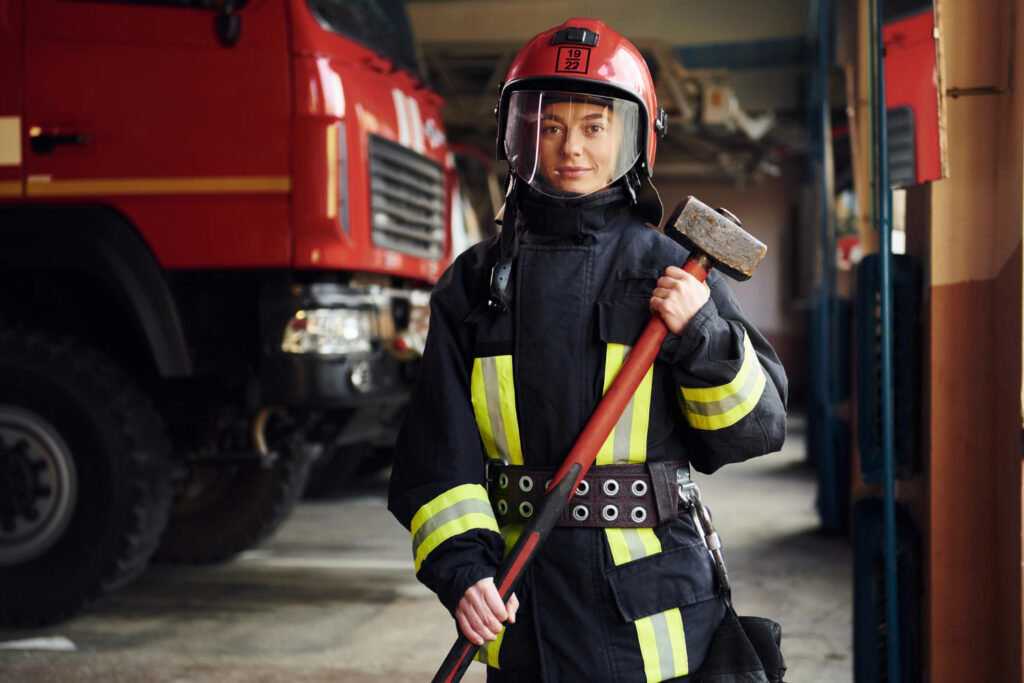 Feuerwehrfrau mit Vorschlaghammer in der Fahrzeughalle